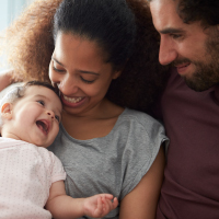 A young couple holding a laughing baby