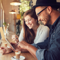 a young couple looking at a mobile phone at coffee shop