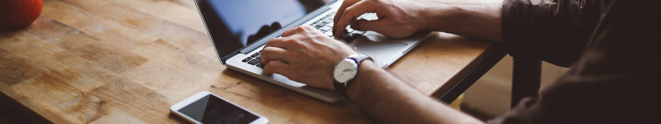 man working on laptop with cell phone near