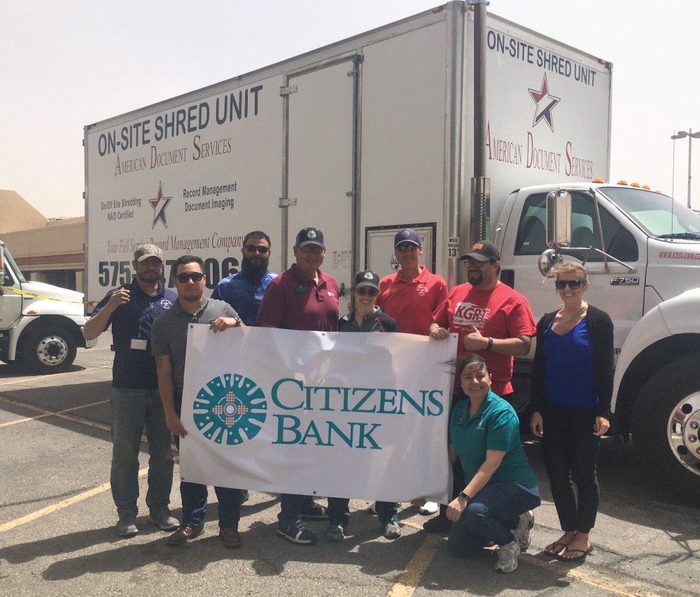bank staff and ADS staff holding a bank banner in front of a shred truck