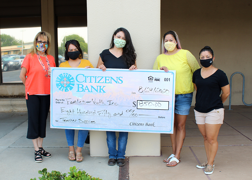 Bank staff poses with volunteers from Families And Youth Inc with a large check